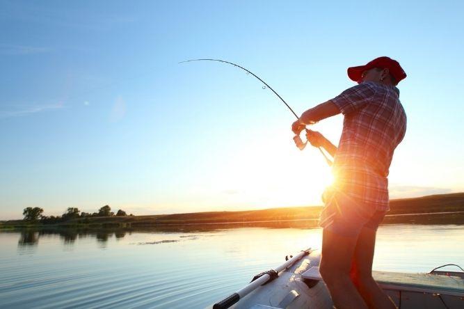 man fishing on boat at sunset using his fishfinder